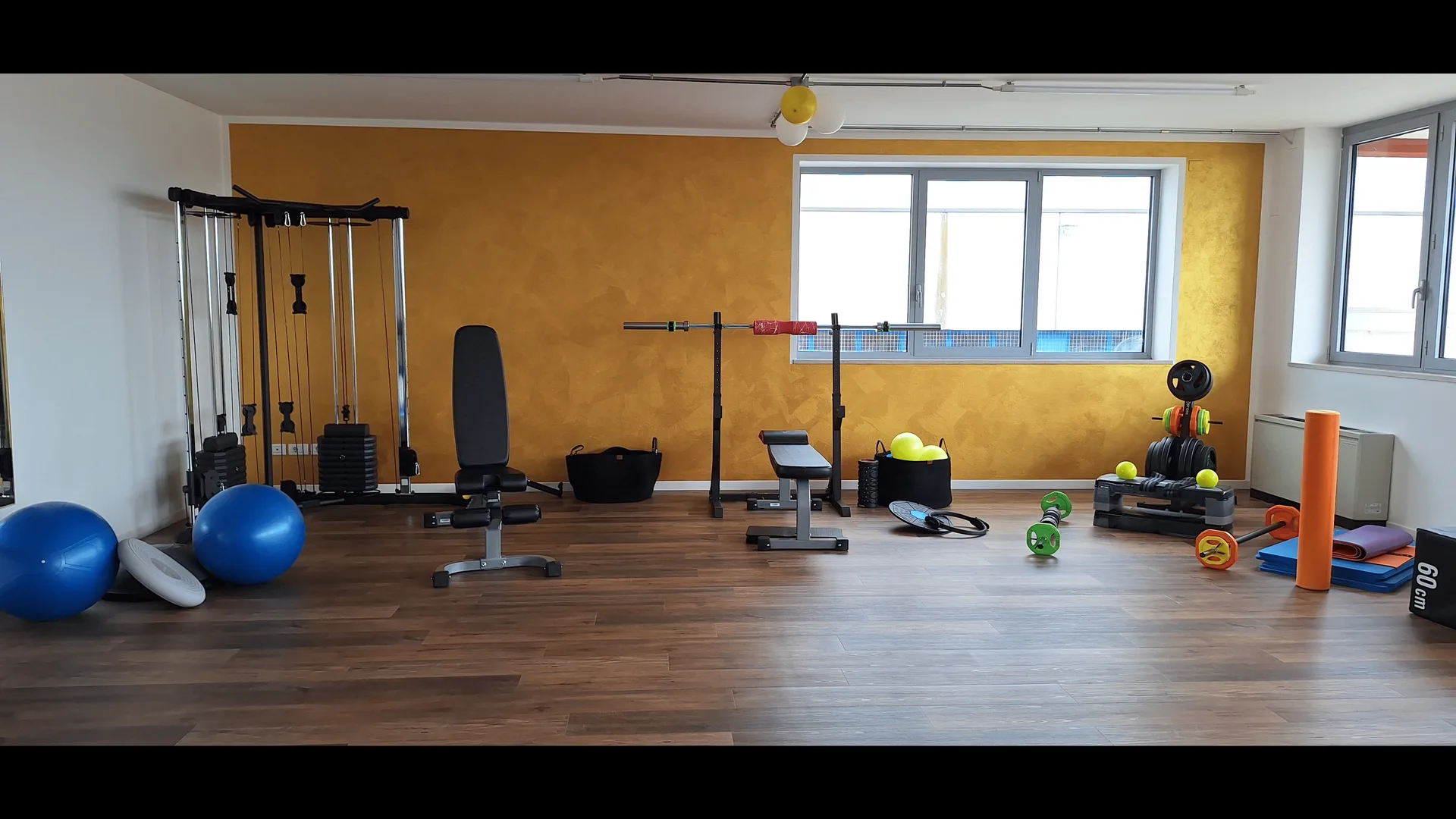 La sala attrezzi di Humana Fitness Lab, con la parete gialla e le grandi finestre